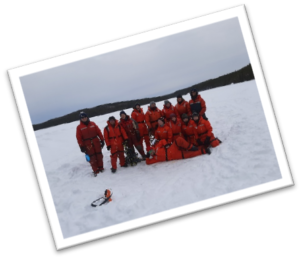 People dressed in red snowsuits on snowy lake